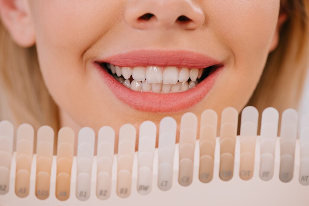 cropped view of smiling woman holding teeth color