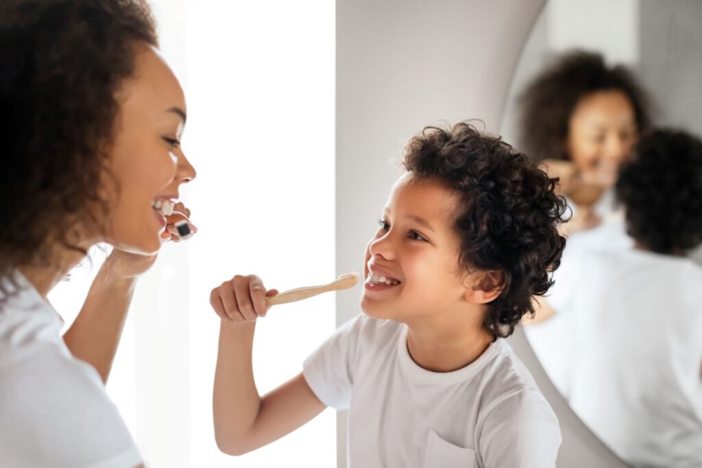 happy child and mother brushing teeth together